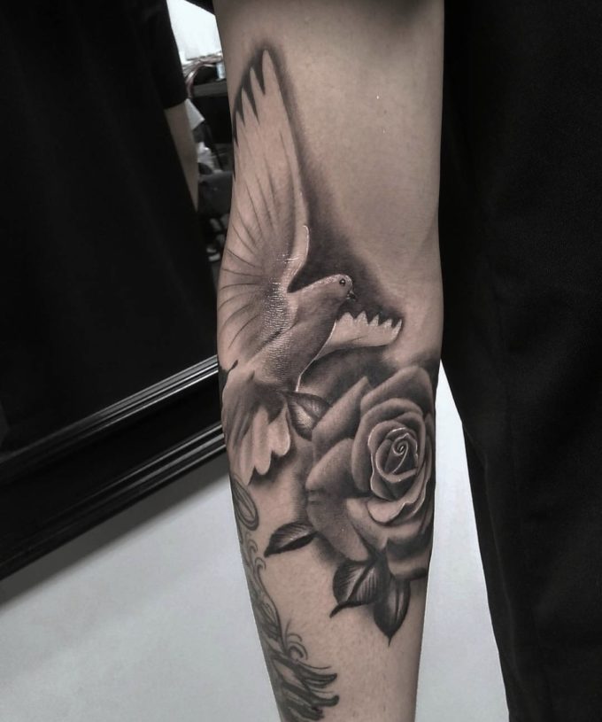 black and white dove with rose tattoo on arm