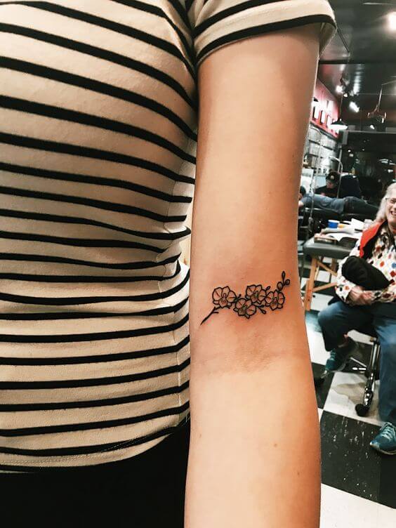 tiny outlined orchid flower tattoo on inner arm