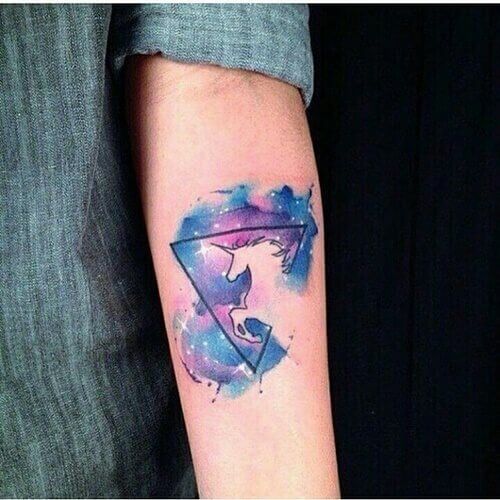 geometric watercolor unicorn astronomy tattoo on forearm