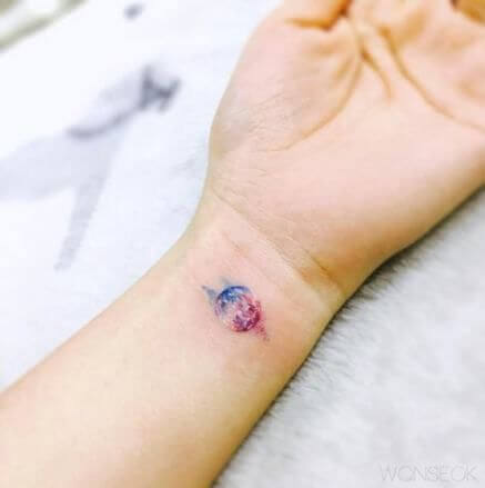 small watercolor planet tattoo on wrist