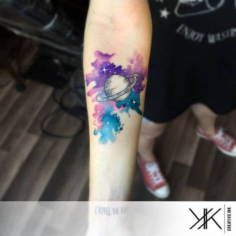 watercolor universe astronomy tattoo on forearm