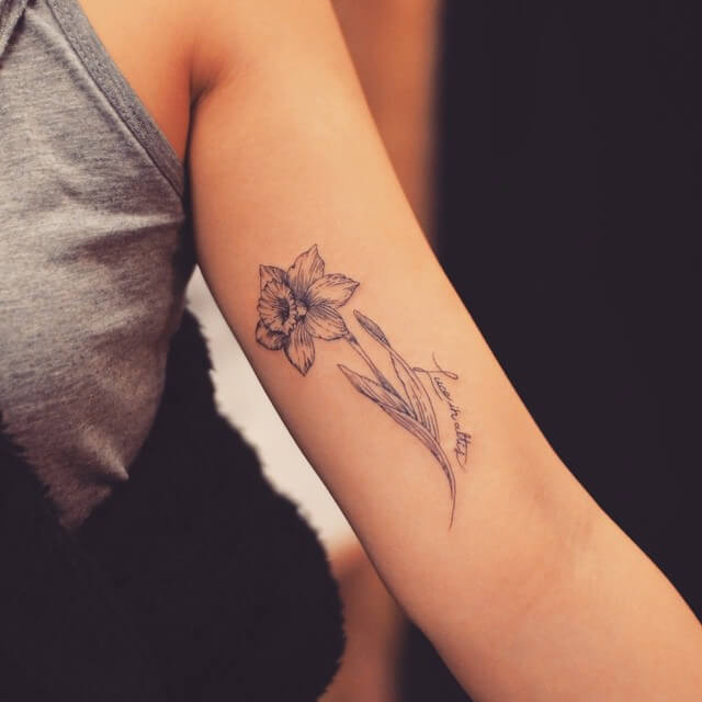december birth flower with quote tattoo on upper arm