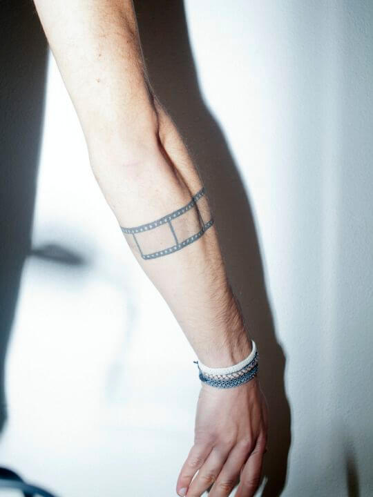film strip black band tattoo design on forearm