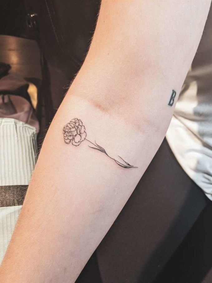 small black and white horizontal carnation January tattoo design on forearm