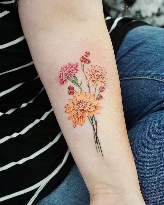 bunch of yellow and pink carnation January birth flowers tattoo design on forearm