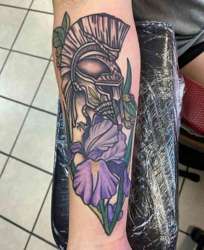 Greek knight helmet with purple iris flowers tattoo design on forearm