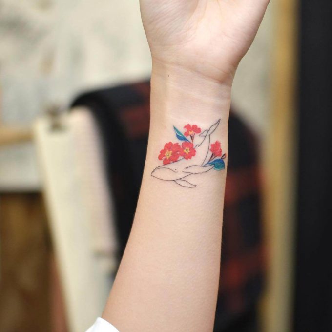 outline whale with primroses tattoo on wrist