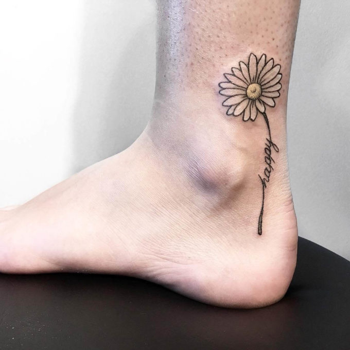outline gerbera daisy tattoo design with happy text on ankle for females