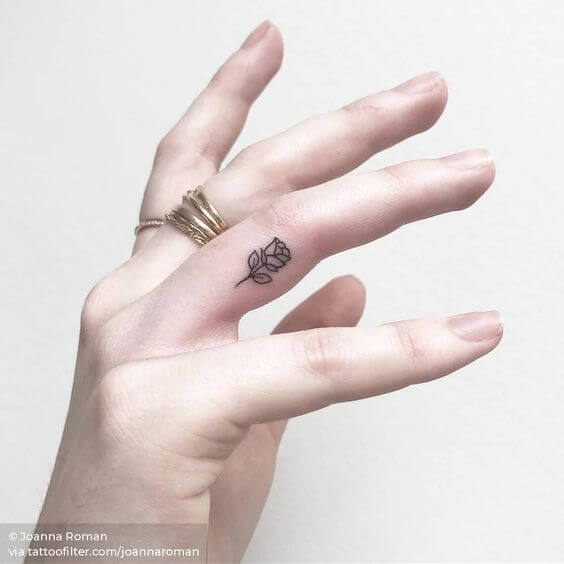 outline minimal rose tattoo design idea on side ring finger for females