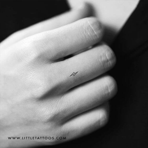 tiny minimal lightning bolt tattoo design idea on middle finger