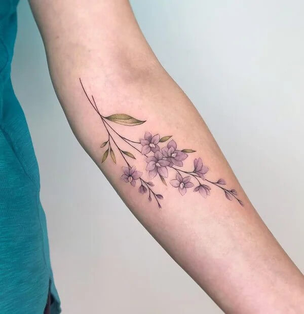 minimalist larkspur july birth flower tattoo design idea on forearm