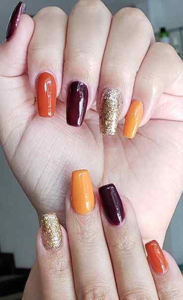 glitter gold with muted orange and purple nails