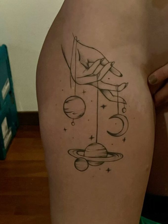 hand with strings of planets space themed tattoo design